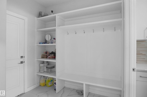 Built-in white cabinetry featuring open shelving, integrated hooks, and a lower bench - 4003 39 Street, Beaumont, AB - Indoor