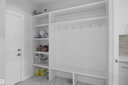Built-in white cabinetry featuring open shelving, integrated hooks, and a lower bench - 
