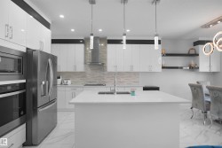Modern kitchen featuring a large center island, integrated stainless steel appliances, white cabinetry with contemporary hardware, a tiled backsplash, and recessed and pendant lighting - 