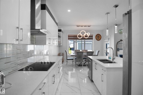 Modern kitchen featuring white glossy cabinetry, a stainless steel range hood, and a built-in cooktop - 4003 39 Street, Beaumont, AB - Indoor Photo Showing Kitchen With Double Sink With Upgraded Kitchen