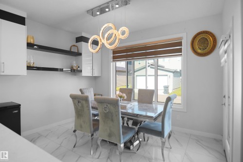 Dining area featuring a contemporary chandelier, white cabinetry, open shelving, and large format tile flooring - 4003 39 Street, Beaumont, AB - Indoor Photo Showing Dining Room