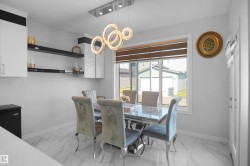 Dining area featuring a contemporary chandelier, white cabinetry, open shelving, and large format tile flooring - 
