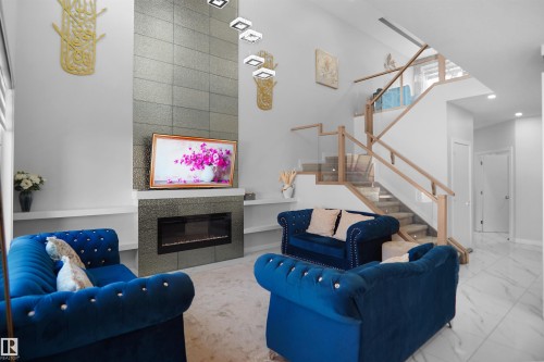 Living area featuring a floor-to-ceiling fireplace with tiled surround, a contemporary chandelier, and built-in shelving - 4003 39 Street, Beaumont, AB - Indoor Photo Showing Living Room With Fireplace