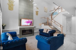 Living area featuring a floor-to-ceiling fireplace with tiled surround, a contemporary chandelier, and built-in shelving - 