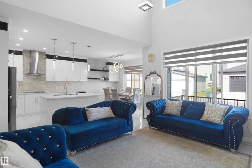 Open-concept living space featuring a two-story ceiling, large windows with horizontal blinds, recessed lighting, and a modern kitchen - 4003 39 Street, Beaumont, AB - Indoor Photo Showing Living Room