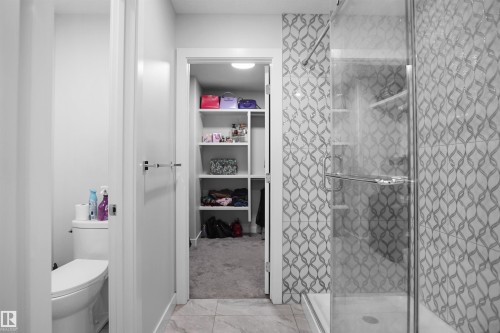 Glass-enclosed shower featuring a patterned tile surround - 4003 39 Street, Beaumont, AB - Indoor Photo Showing Bathroom