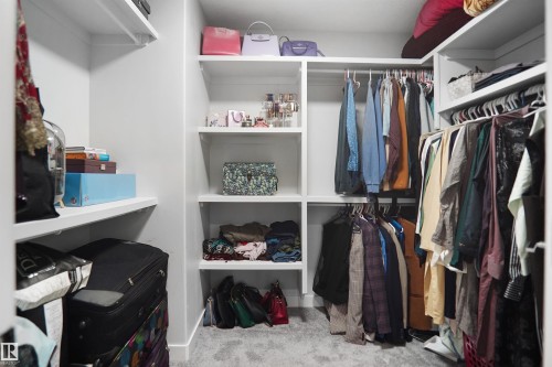 Built-in closet system featuring white shelving, multiple hanging rods, and light gray carpet flooring - 4003 39 Street, Beaumont, AB - Indoor With Storage
