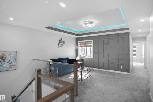 Upper level living area featuring a decorative accent wall, recessed ceiling with accent lighting, and light-tone carpet flooring - 4003 39 Street, Beaumont, AB - Indoor Photo Showing Other Room