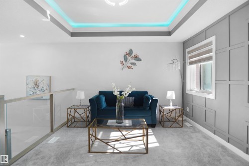 Carpeted loft space featuring a tray ceiling with accent lighting, a paneled accent wall, a large window, and a glass railing - 4003 39 Street, Beaumont, AB - Indoor