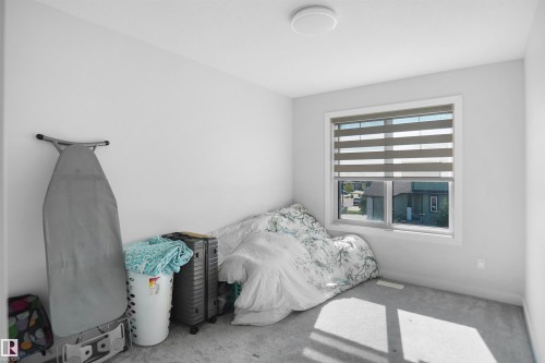 Recessed window with layered horizontal blinds, flush-mount ceiling light fixture, and light gray carpeted flooring - 4003 39 Street, Beaumont, AB - Indoor Photo Showing Bedroom