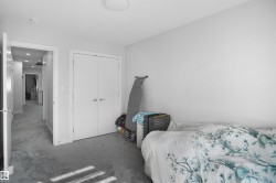 Recessed lighting illuminates a hallway featuring light gray walls and plush gray carpeting - 