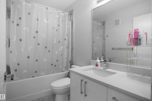 Contemporary bathroom featuring a white vanity with integrated sink, chrome faucet, and expansive wall mirror - 4003 39 Street, Beaumont, AB - Indoor Photo Showing Bathroom