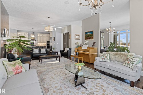 Living room with a chandelier, a textured ceiling, healthy amount of natural light, and wood finished floors - 2796 Wheaton Drive Nw, Edmonton, AB - Indoor Photo Showing Living Room