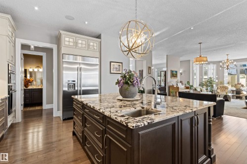 Kitchen featuring a chandelier, light stone countertops, hanging light fixtures, dark brown cabinetry, and a textured ceiling - 2796 Wheaton Drive Nw, Edmonton, AB - Indoor Photo Showing Kitchen With Upgraded Kitchen