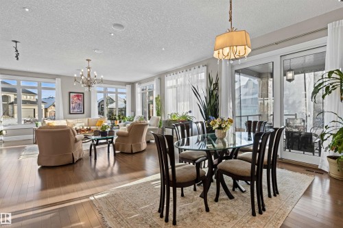 Dining space with a chandelier, wood-type flooring, and a textured ceiling - 2796 Wheaton Drive Nw, Edmonton, AB - Indoor Photo Showing Dining Room