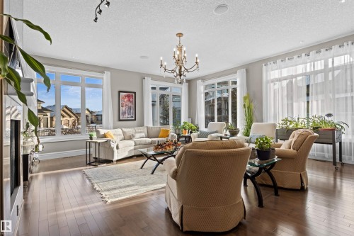 Living area featuring a chandelier, dark wood-style floors, a textured ceiling, and healthy amount of natural light - 2796 Wheaton Drive Nw, Edmonton, AB - Indoor Photo Showing Living Room