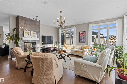 Living room featuring a tile fireplace, dark wood-style flooring, a chandelier, and a textured ceiling - 2796 Wheaton Drive Nw, Edmonton, AB - Indoor Photo Showing Living Room With Fireplace