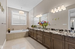 Full bath with a textured ceiling, double vanity, light tile patterned floors, a garden tub, and a chandelier - 