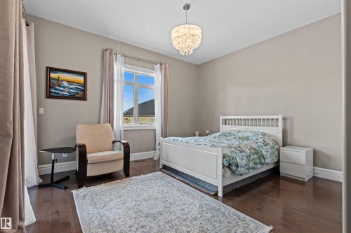 Bedroom with dark wood-style flooring, a chandelier, and a textured ceiling - 2796 Wheaton Drive Nw, Edmonton, AB - Indoor Photo Showing Bedroom