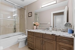 Bathroom featuring vanity, a textured ceiling, bath / shower combo with glass door, and light tile patterned floors - 