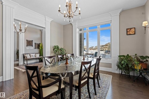 Dining room featuring a chandelier, dark wood finished floors, decorative columns, and a textured ceiling - 2796 Wheaton Drive Nw, Edmonton, AB - Indoor Photo Showing Dining Room