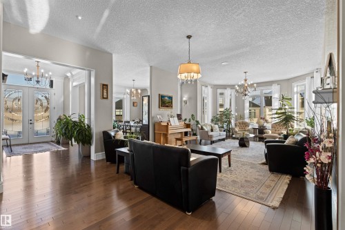Living room featuring dark wood-style flooring, a chandelier, french doors, and a textured ceiling - 2796 Wheaton Drive Nw, Edmonton, AB - Indoor Photo Showing Living Room