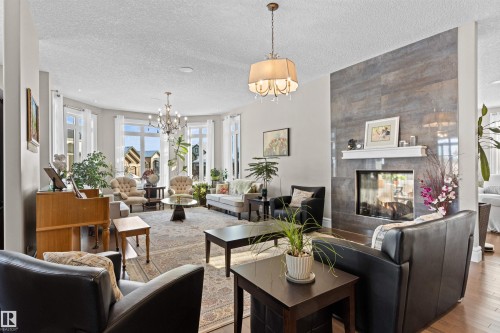 Living area featuring a fireplace, a chandelier, hardwood / wood-style floors, and a textured ceiling - 2796 Wheaton Drive Nw, Edmonton, AB - Indoor Photo Showing Living Room With Fireplace