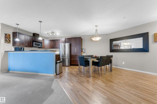 Open-concept kitchen and dining area with wood-finish flooring - #136 16035 132 St Nw, Edmonton, AB - Indoor