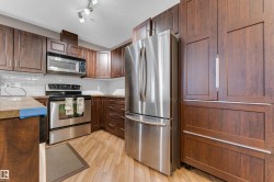 Kitchen featuring wood-finish cabinetry, stainless steel appliances, light wood-finish flooring, subway tile backsplash, and track lighting - 
