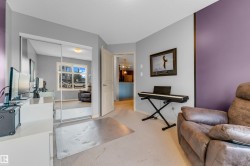 Room featuring light gray and purple accent walls, light-colored carpeting, a doorway with an interior light fixture visible, and a mirrored closet - 