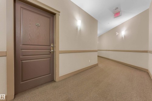 Corridor featuring textured carpeting and neutral paint with chair rail molding - #136 16035 132 St Nw, Edmonton, AB - Indoor Photo Showing Other Room