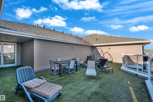 Rooftop deck featuring artificial turf, a glass safety barrier, and exterior wall sconces - #136 16035 132 St Nw, Edmonton, AB - Outdoor With Deck Patio Veranda