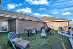 Rooftop deck featuring artificial turf, a glass safety barrier, and exterior wall sconces - 