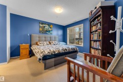 Carpeted bedroom featuring a large window, recessed lighting, and a built-in dark wood bookcase - 
