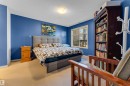 Carpeted bedroom featuring a large window, recessed lighting, and a built-in dark wood bookcase - #136 16035 132 St Nw, Edmonton, AB  - Indoor Photo Showing Bedroom 