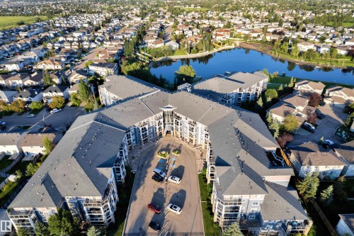 Multi-story residential complex featuring a central courtyard entrance and numerous private balconies - #136 16035 132 St Nw, Edmonton, AB - Outdoor With Body Of Water With View