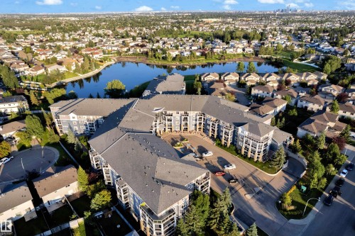 Multi-story condominium complex with multiple balconies and a central parking area - #136 16035 132 St Nw, Edmonton, AB - Outdoor With Body Of Water With View