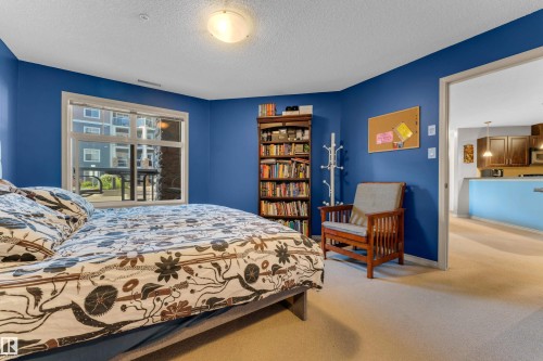 Bedroom with blue painted walls and neutral carpeting - #136 16035 132 St Nw, Edmonton, AB - Indoor Photo Showing Bedroom