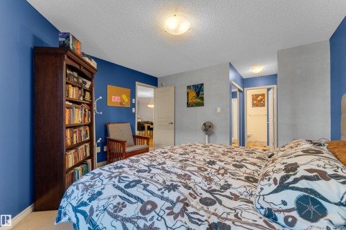 Bedroom featuring blue and grey painted walls, a built-in bookshelf, and carpeting - #136 16035 132 St Nw, Edmonton, AB - Indoor Photo Showing Bedroom
