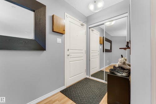 Entryway featuring wood-finish flooring, light gray wall paint, and a modern ceiling light fixture - #136 16035 132 St Nw, Edmonton, AB - Indoor Photo Showing Other Room