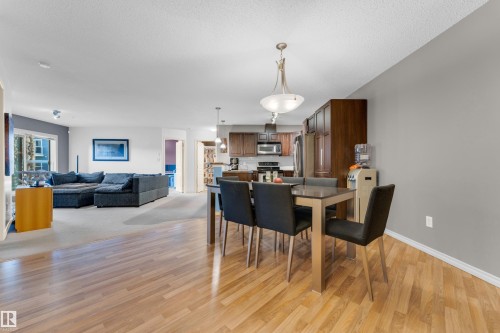 Spacious dining area featuring wood-finish flooring, an overhead decorative light fixture, and contemporary wall colors - #136 16035 132 St Nw, Edmonton, AB - Indoor Photo Showing Dining Room