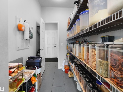 Utility room with extensive built-in wire shelving, gray tile flooring, and a solid panel interior door - 1716 60 Street Sw, Edmonton, AB - Indoor