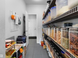 Utility room with extensive built-in wire shelving, gray tile flooring, and a solid panel interior door - 