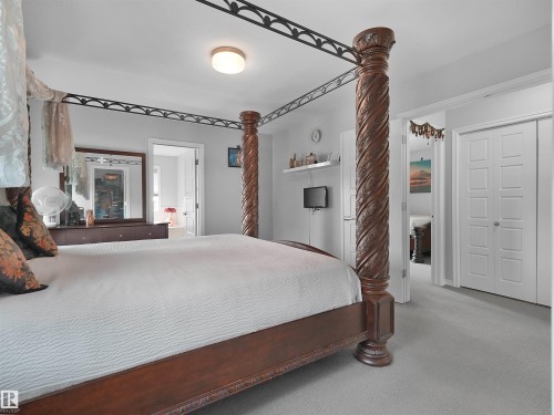 Carpeted bedroom featuring a four-poster bed with carved wood columns and wrought iron detailing - 1716 60 Street Sw, Edmonton, AB - Indoor Photo Showing Bedroom