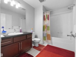 Bathroom featuring a dark wood-finish vanity with a single basin sink, a large wall-mounted mirror, and a full bathtub with an overhead shower - 
