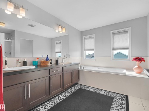 Spacious bathroom featuring a dual vanity with dark wood cabinetry and a large mirror - 1716 60 Street Sw, Edmonton, AB - Indoor Photo Showing Bathroom