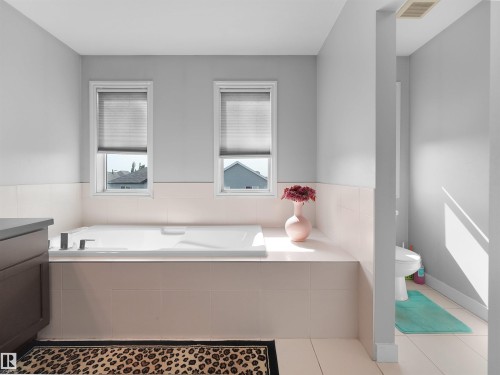 Alcove bathtub with deck-mounted fixtures, surrounded by light-toned tilework - 1716 60 Street Sw, Edmonton, AB - Indoor Photo Showing Bathroom