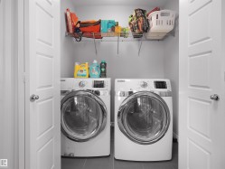 Dedicated laundry space featuring a side-by-side washer and dryer, tile flooring, and integrated wire shelving for storage - 