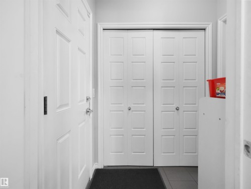 Entryway featuring a paneled door with polished hardware, dual bi-fold closet doors, and tile flooring - 1716 60 Street Sw, Edmonton, AB - Indoor Photo Showing Other Room