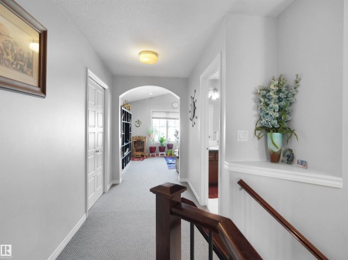 Carpeted hallway with light gray walls, an arched entryway, and a built-in shelf - 1716 60 Street Sw, Edmonton, AB - Indoor Photo Showing Other Room